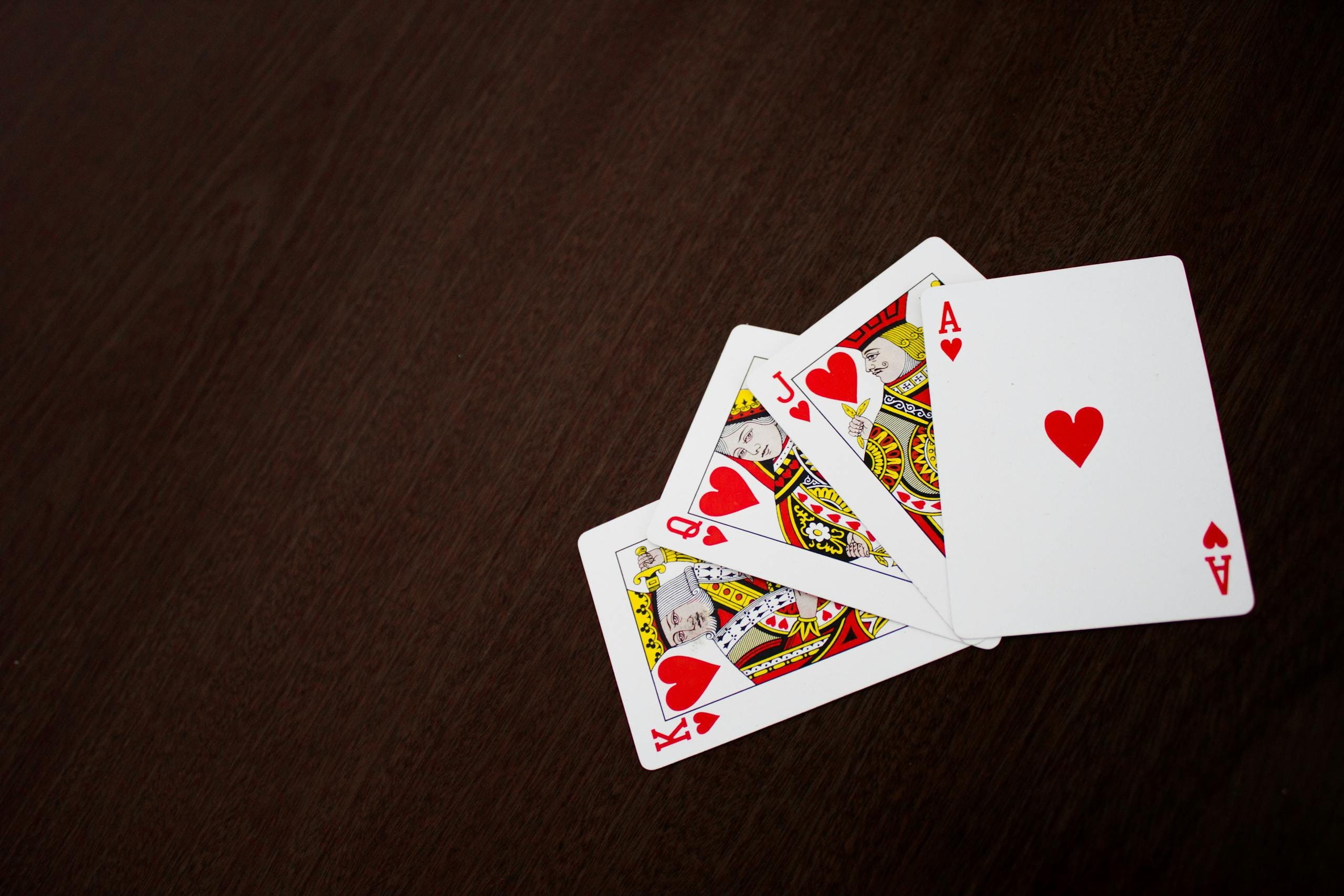 Elegant flat lay of playing cards featuring ace of hearts on a wooden surface.
